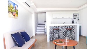 A modern living space with a sofa, a dining table, a kitchen area with a microwave, and a staircase leading to an upper level. - Villa Marlin, Cancun Caribe, Ocean front (Cancún)