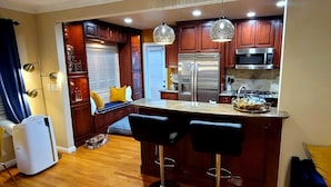 A modern kitchen with dark wood cabinets, stainless steel appliances, and a central island with bar stools.
