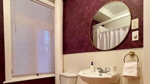 A bathroom with a toilet, sink, and mirror. - Nice Condo in Limoilou (Quebec City)