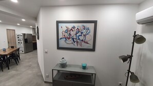 Une cuisine moderne avec un coin repas, un réfrigérateur, une machine à café et une œuvre d’art accrochée au mur.