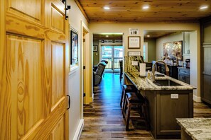 A wooden interior hallway leading to a kitchen area with a marble countertop and bar stools. - Sugar Ski Two Bedroom - Unit 515 (Sugar Mountain)