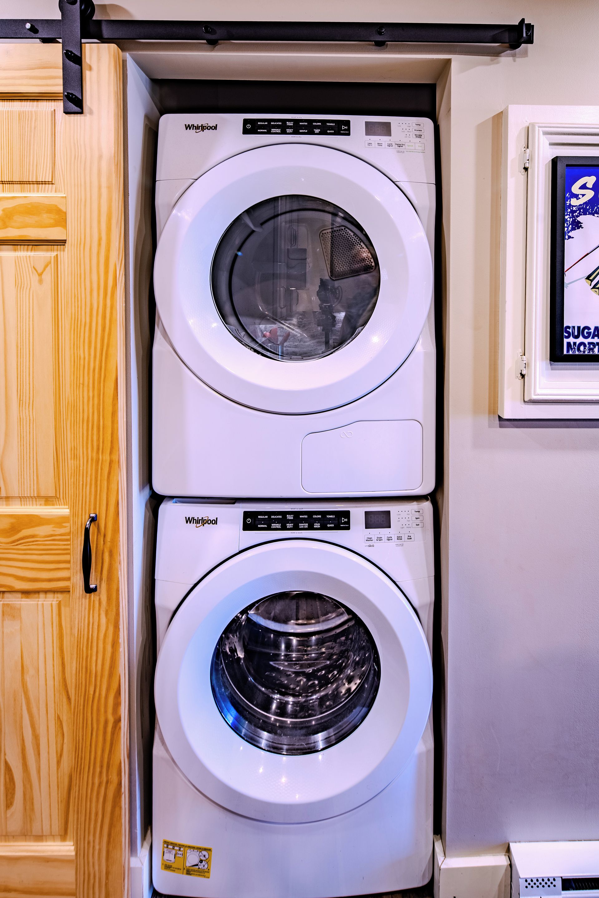 Una unidad de lavadora y secadora Whirlpool de carga frontal, instalada dentro de un armario de cocina.
