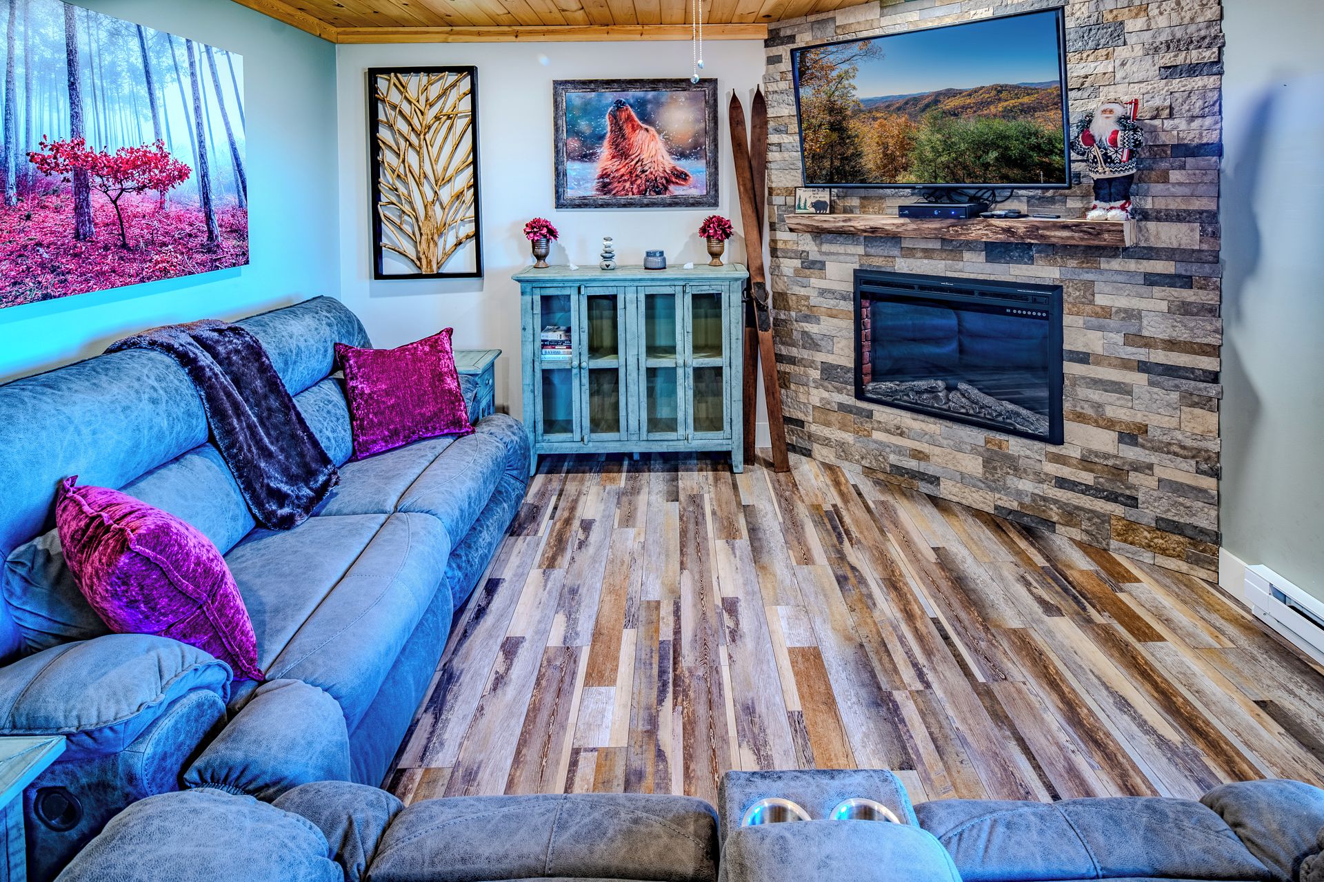 A cozy living room with a blue sofa, a fireplace, and a TV mounted on the wall.