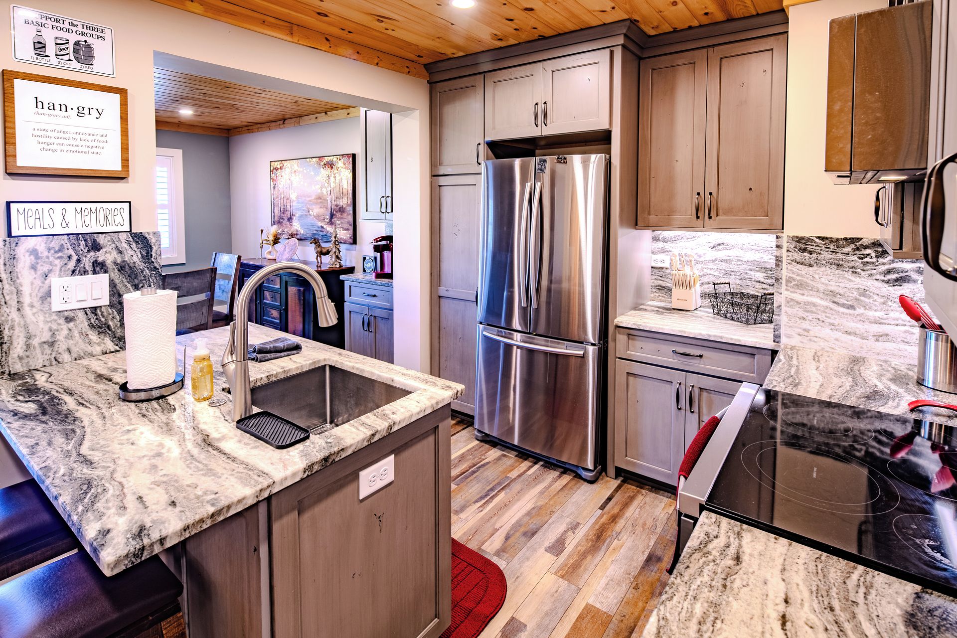 A modern kitchen with stainless steel appliances, marble countertops, and wooden cabinets.