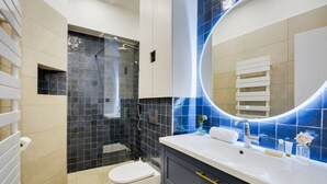 Une salle de bain moderne équipée d’une douche, de toilettes, d’un meuble-lavabo et d’un grand miroir.