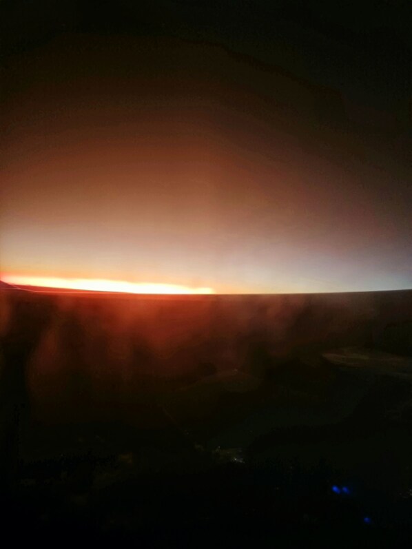 Un coucher de soleil sur un paysage montagneux, avec une rivière au premier plan.