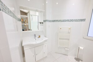 Une salle de bain moderne avec un lavabo blanc, un miroir et des murs carrelés.