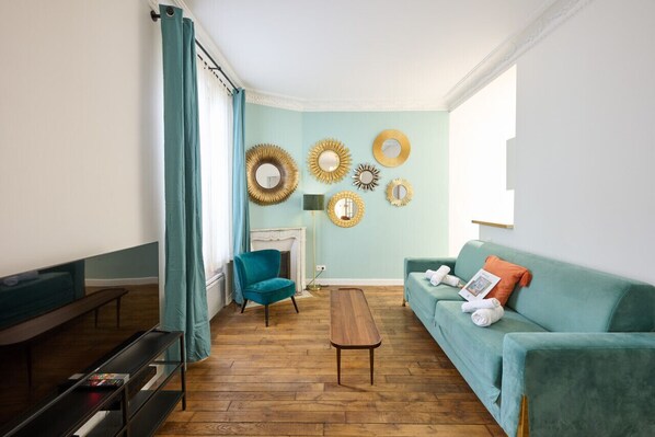 Un salon aux murs de couleur turquoise, avec un fauteuil turquoise, un canapé turquoise, une table basse en bois et une cheminée.