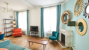 A living room with a fireplace, teal curtains, and a television. - Confort et élégant, proche du parc des expositions (Paris)