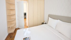 A hotel room with a bed, a wardrobe, and a small table with a lamp. - Confort et élégant, proche du parc des expositions (Paris)