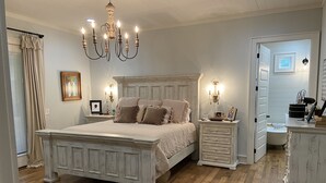 A bedroom with a large bed, a chandelier, a dresser, and a vanity. - 20 min to Bryant Denny Stadium! 5min to public boat landing at Lake Tuscaloosa! (Northport)