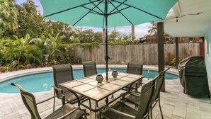 Une terrasse avec une table de billard, des chaises et un grand parasol.
