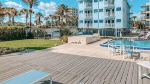 Et resort med poolområde, træterrasse og en bygning med altaner.