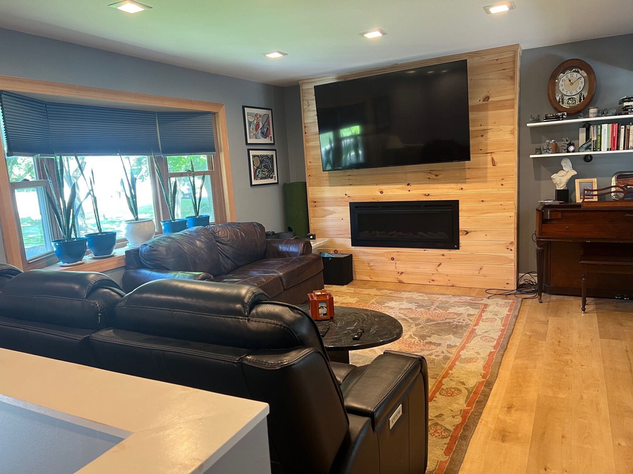 A living room with a leather sofa, a flat-screen TV, a fireplace, and a bookshelf.