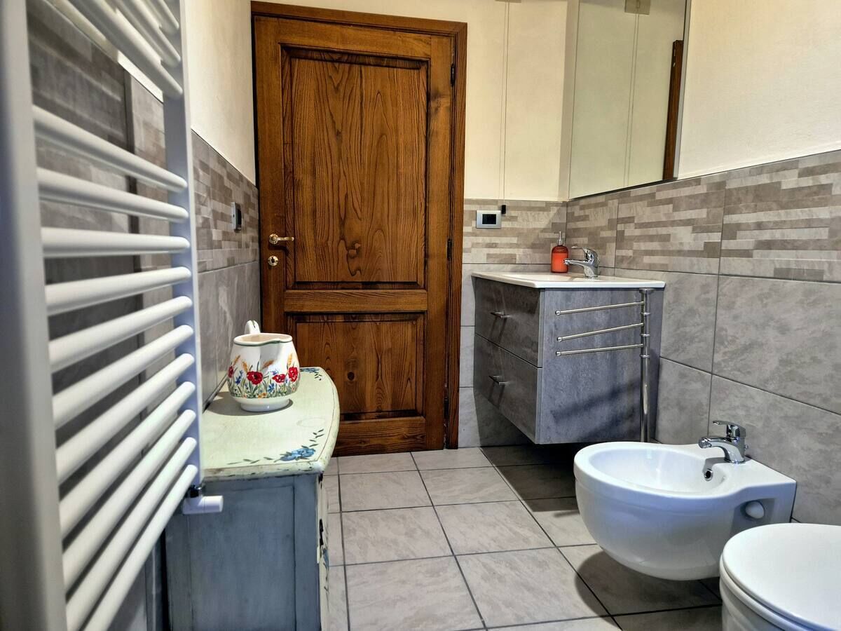 Een badkamer met een houten deur, een wastafel, een bidet en een handdoekhouder.