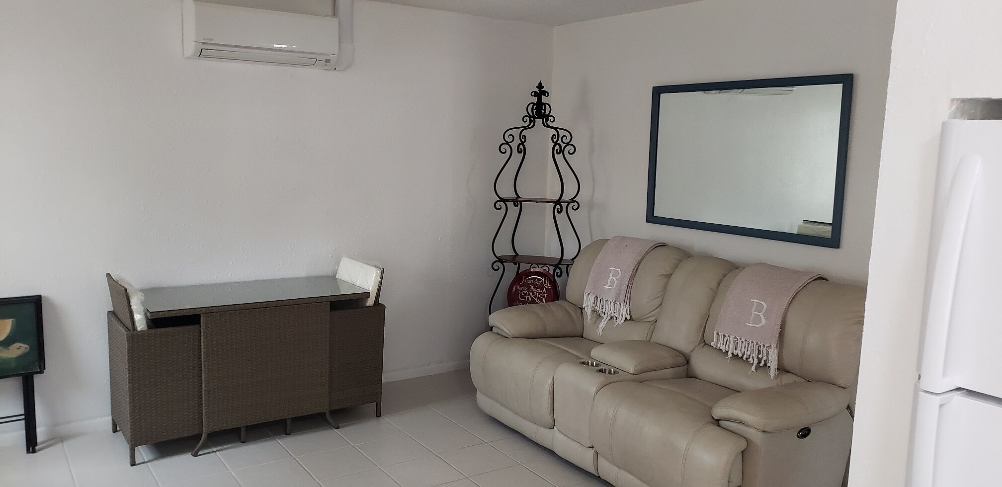 A living room with a beige sofa, a small table, and a wall-mounted mirror.