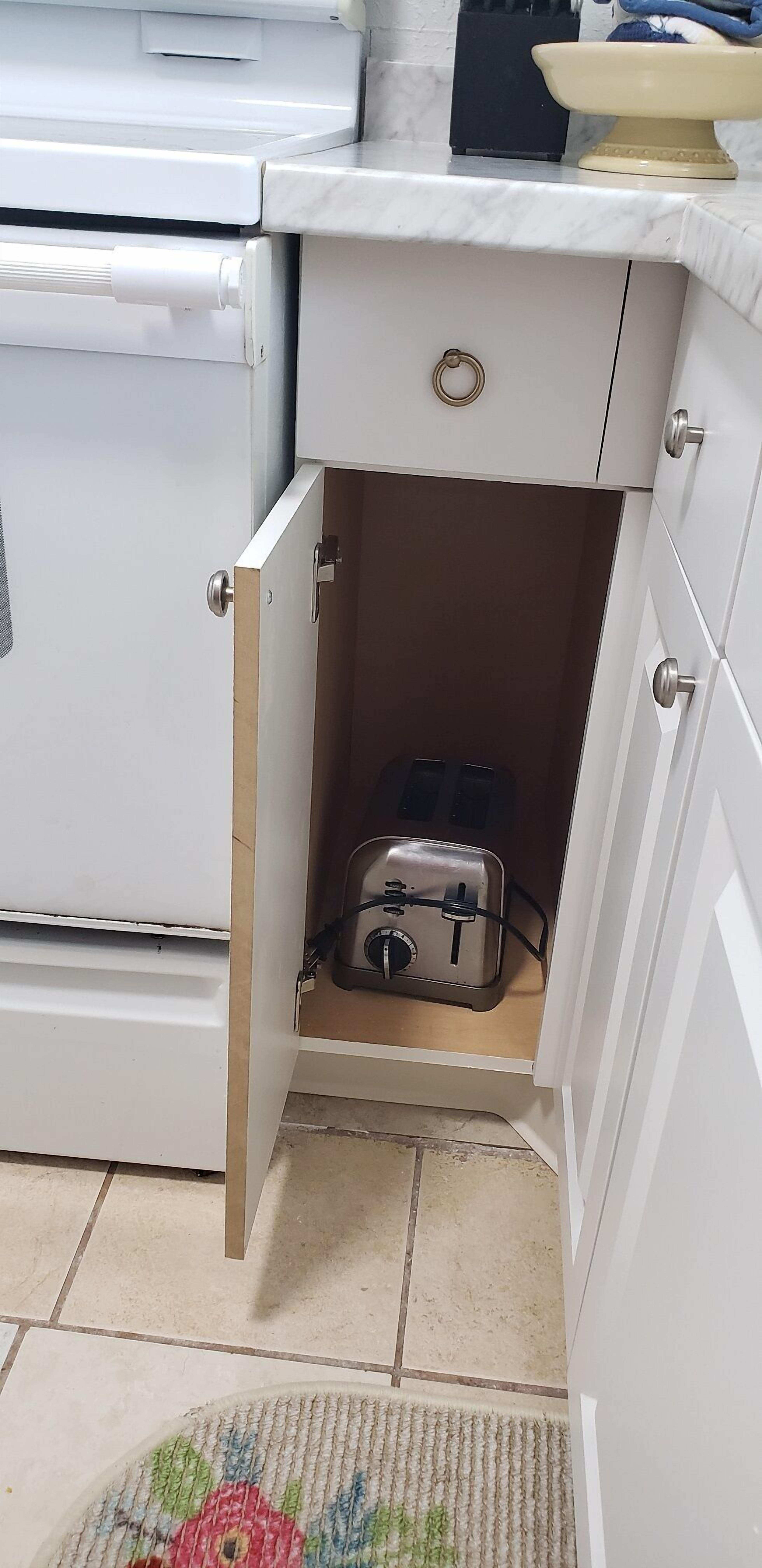 A kitchen with a white stove, a small drawer, and a toaster on the countertop.