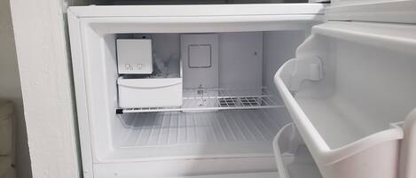 An open refrigerator with a water dispenser and a small freezer compartment.