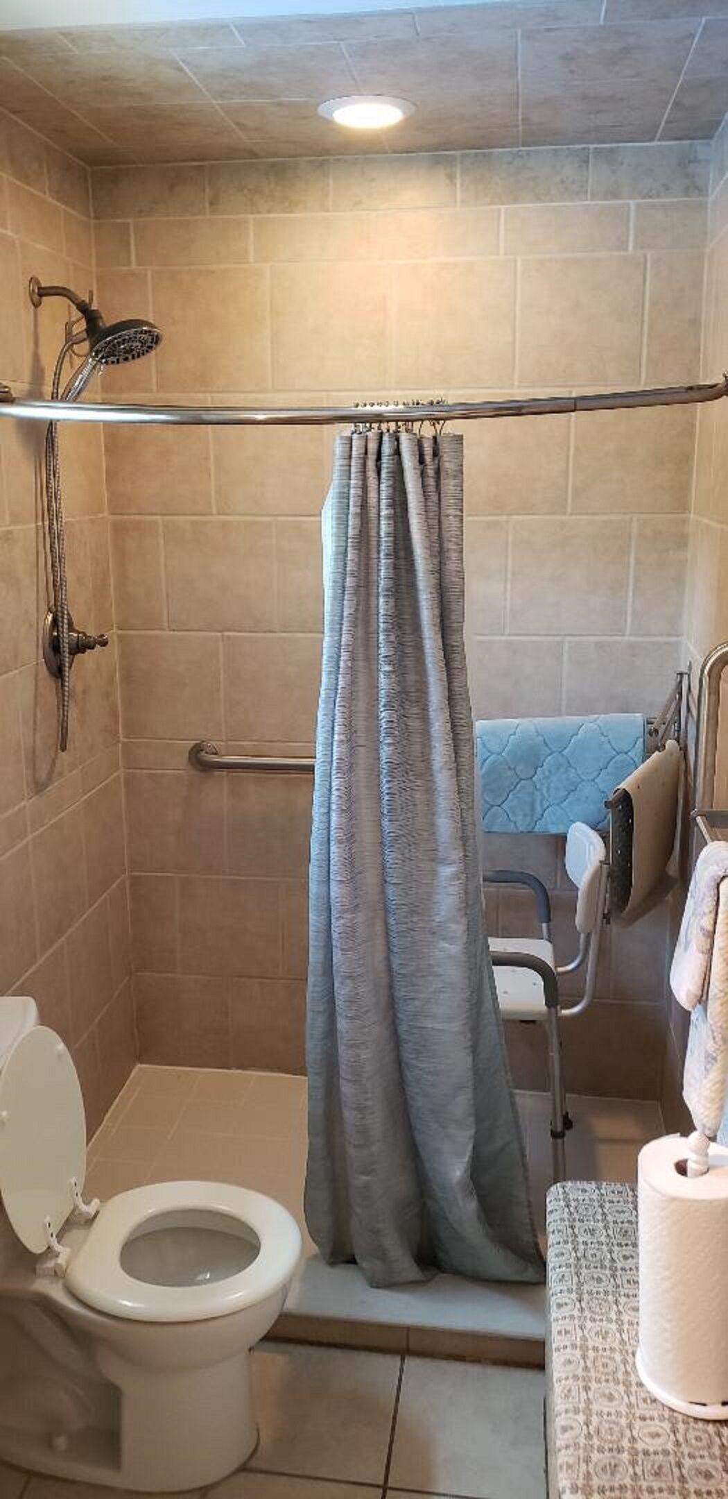 A bathroom with a shower, toilet, and a grab bar.