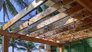 Un patio al aire libre con pérgola, sillas verdes y una mesa.