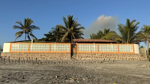 Un edificio con base de piedra y paneles naranja, rodeado de palmeras.