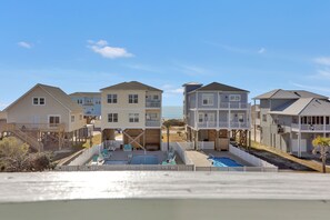 Zona residencial frente a la playa con varias casas, una piscina y una playa al fondo.