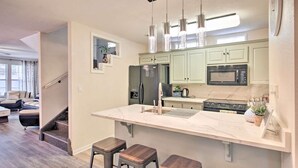 A modern kitchen with a large island, stainless steel appliances, and pendant lighting.