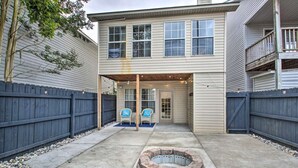 A two-story house with a covered patio area featuring a fire pit and two chairs.