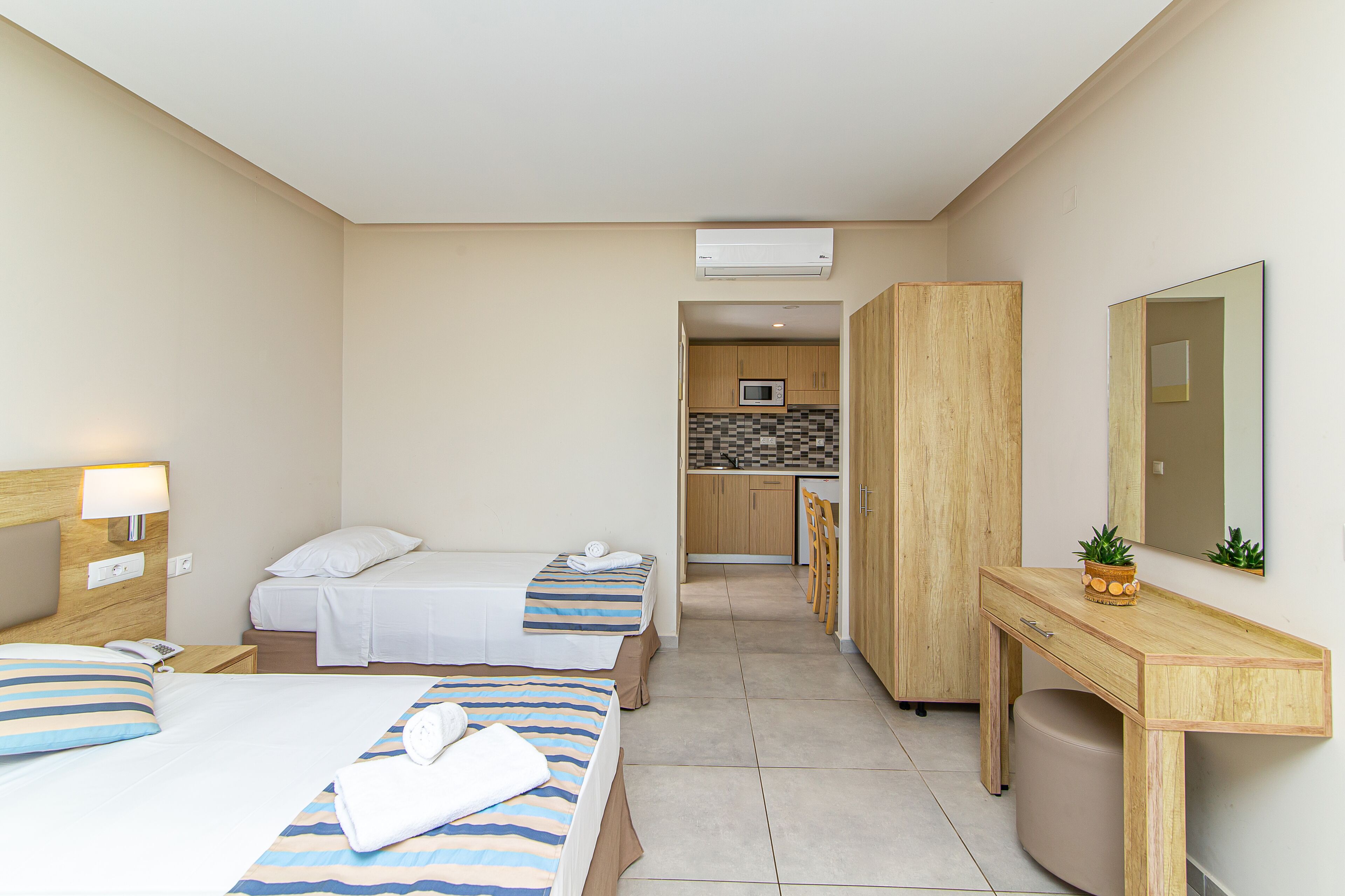 Une chambre d’hôtel avec deux lits, un bureau, une chaise, un four à micro-ondes et une petite kitchenette.