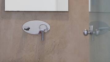 A bathroom with a white sink, a round mirror, and a glass shower enclosure.
