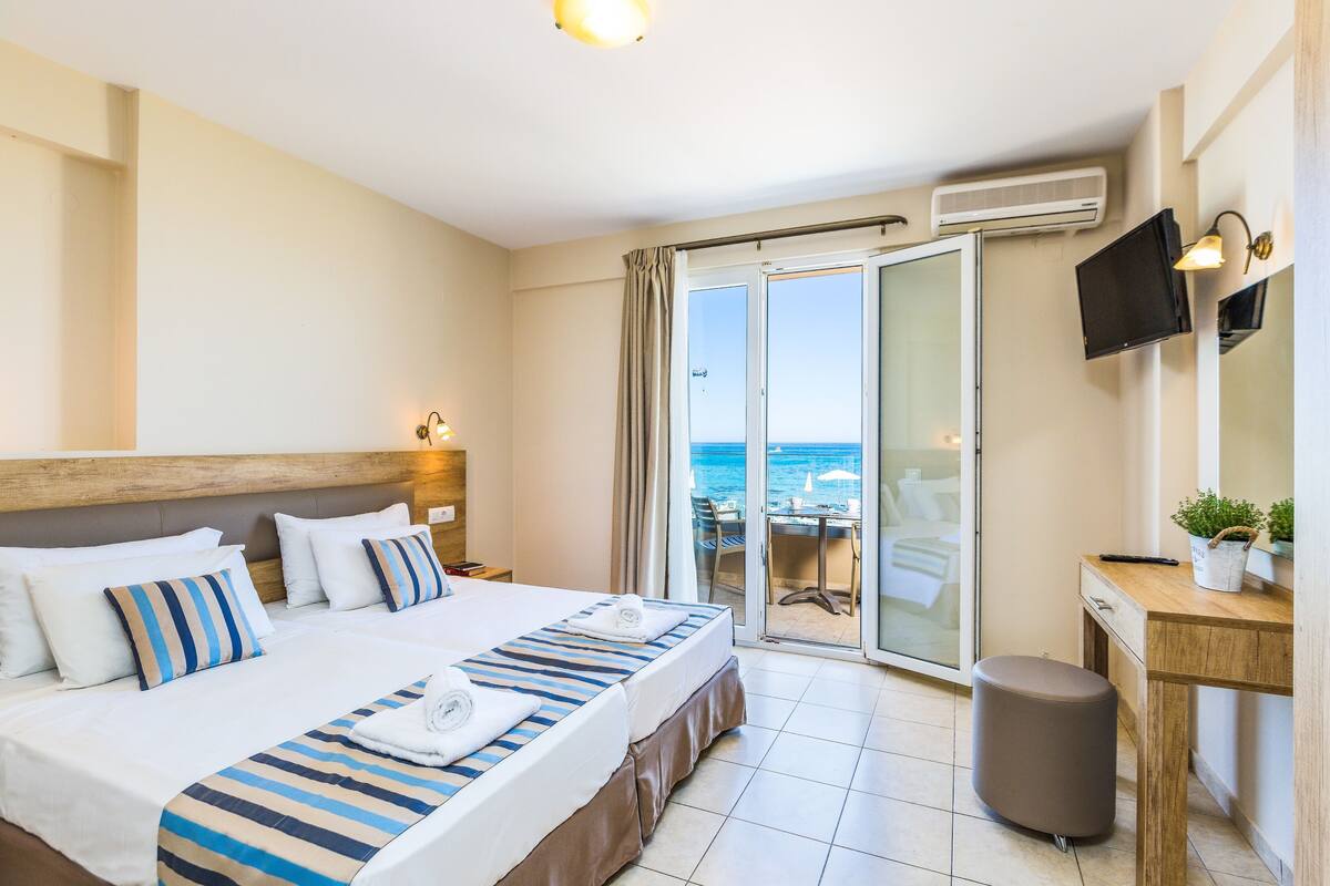 Een hotelkamer met een bed, een bureau, een stoel, een televisie en uitzicht op de oceaan.