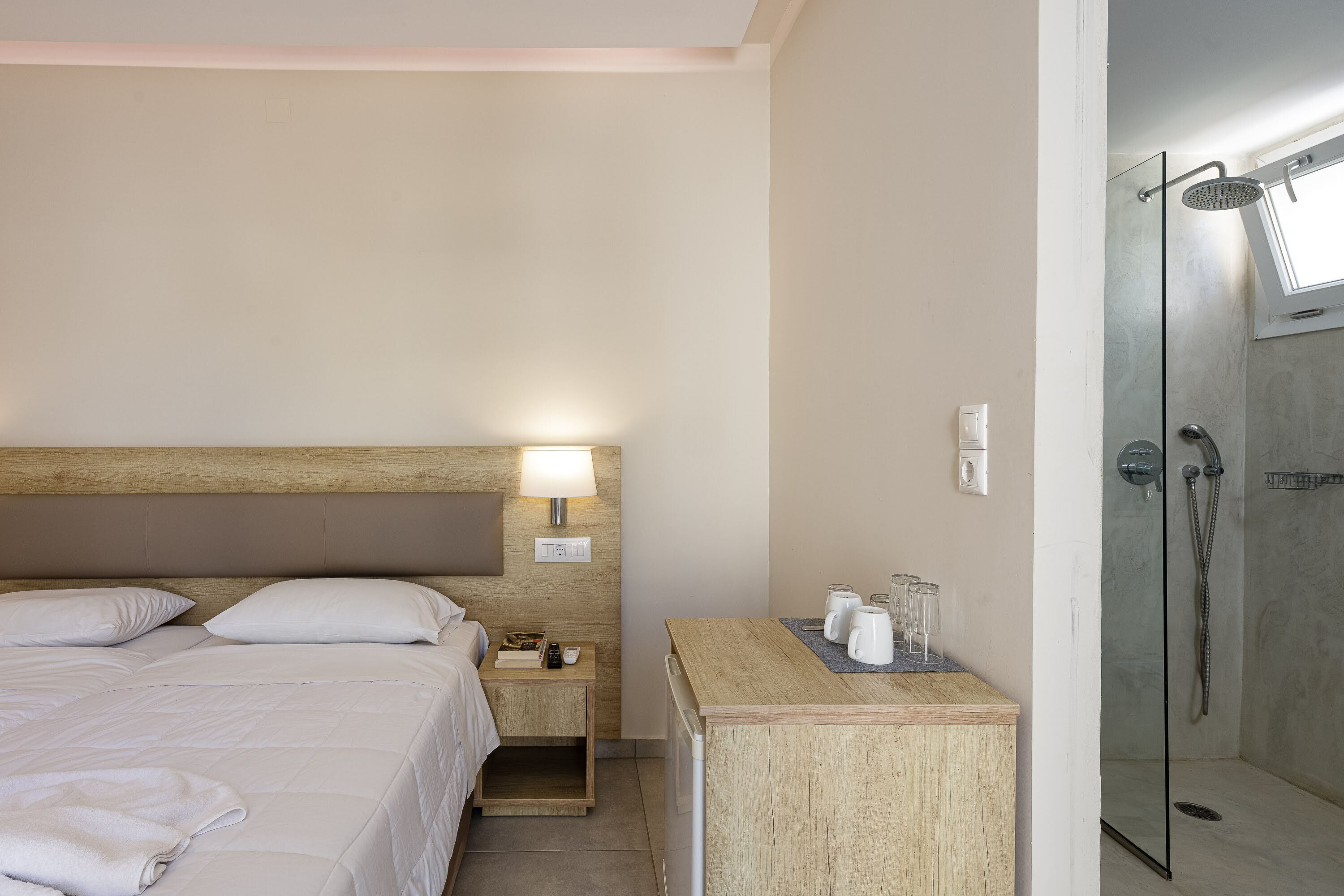 Ein Hotelzimmer mit Bett, Nachttisch, Lampe und Duschbereich.