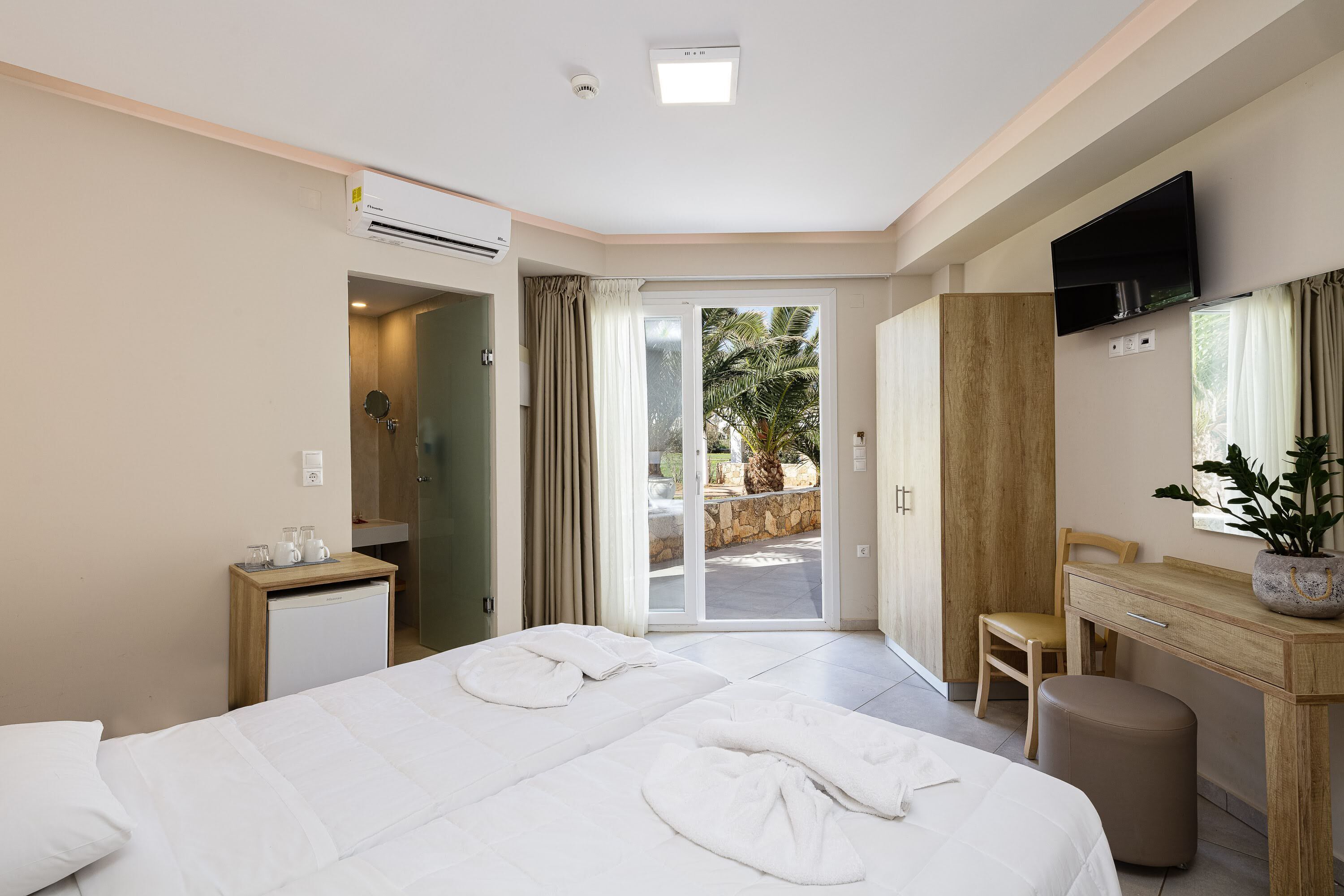Hotelkamer met een bed, een bureau, een stoel, een televisie en uitzicht op het omliggende landschap.