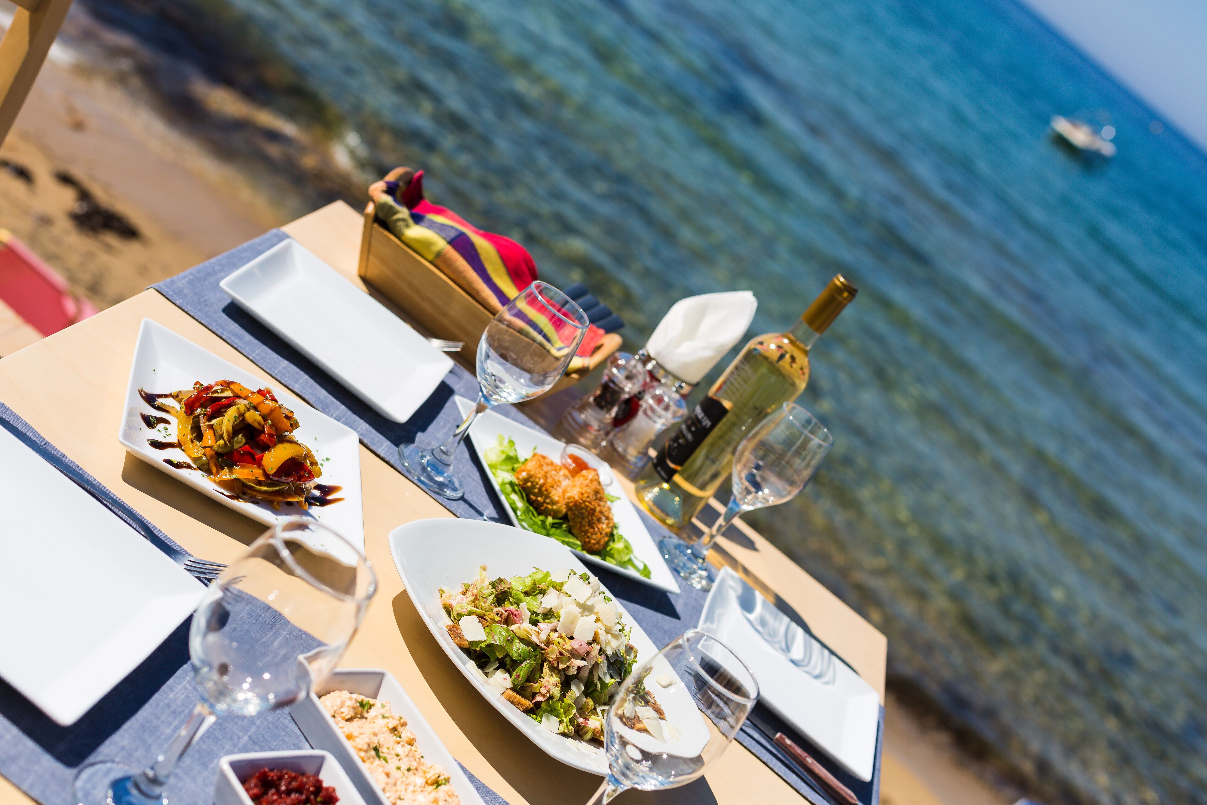 A table set for a meal with various dishes, glasses of wine, and a bottle of champagne.