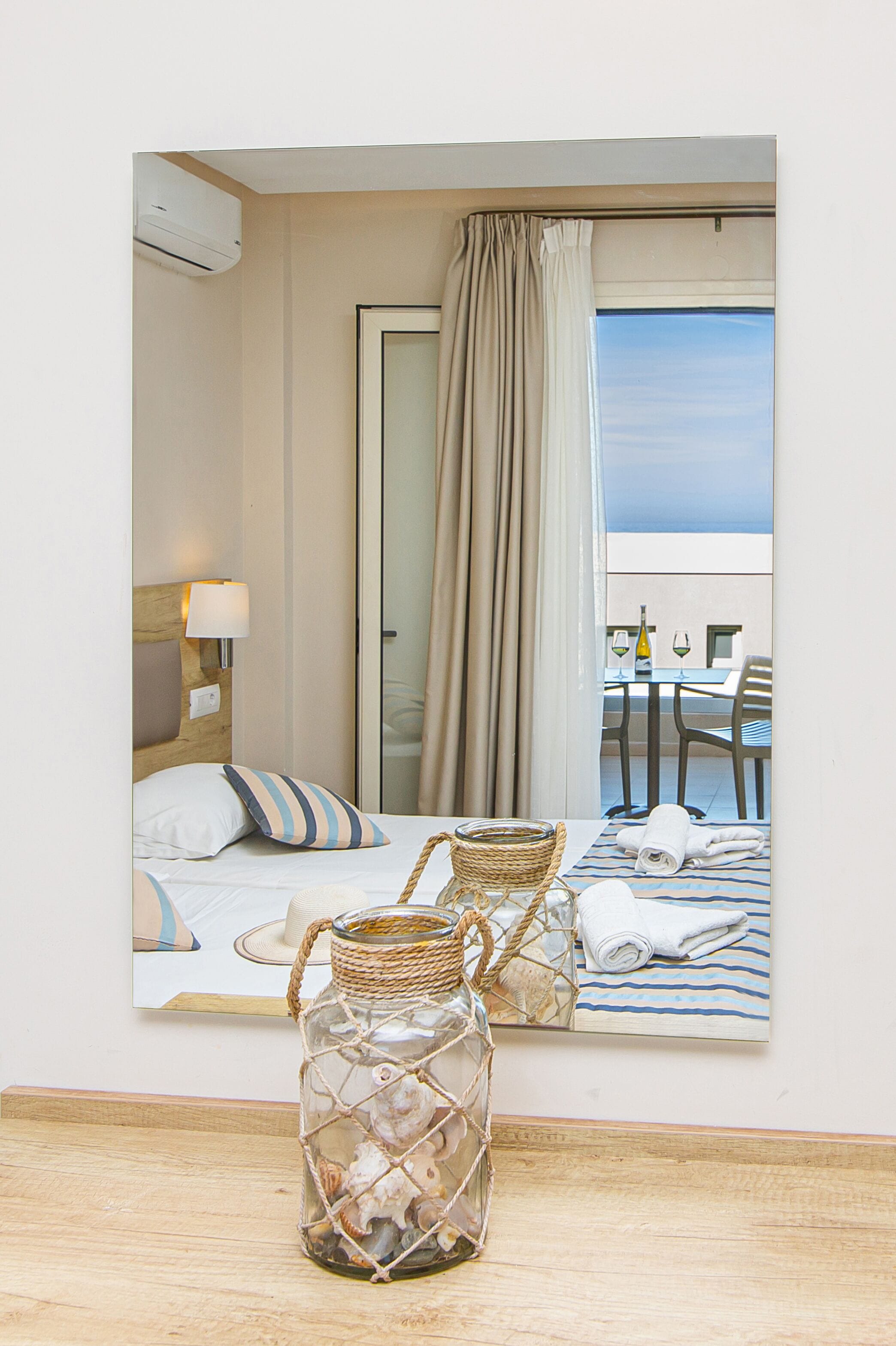 A hotel room with a bed, a bedside lamp, a wicker basket, and a view of the balcony with a table and chairs.
