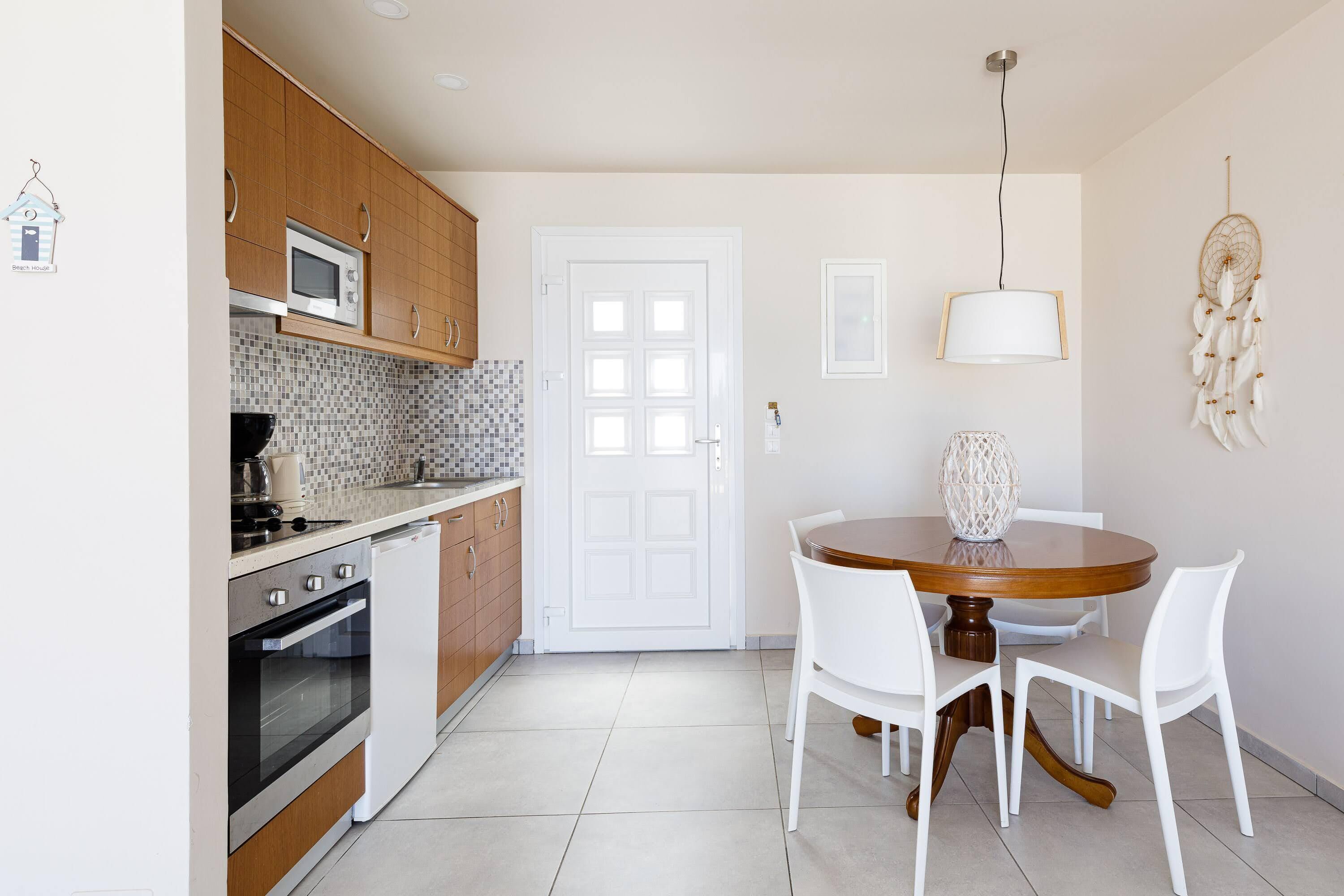 A modern kitchen with wooden cabinets, a microwave, an oven, and a dining area with a round table and white chairs.