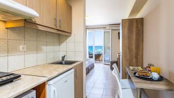 Een compacte keuken met een spoelbak, een vaatwasser en een ontbijtbakje met toast en sap.