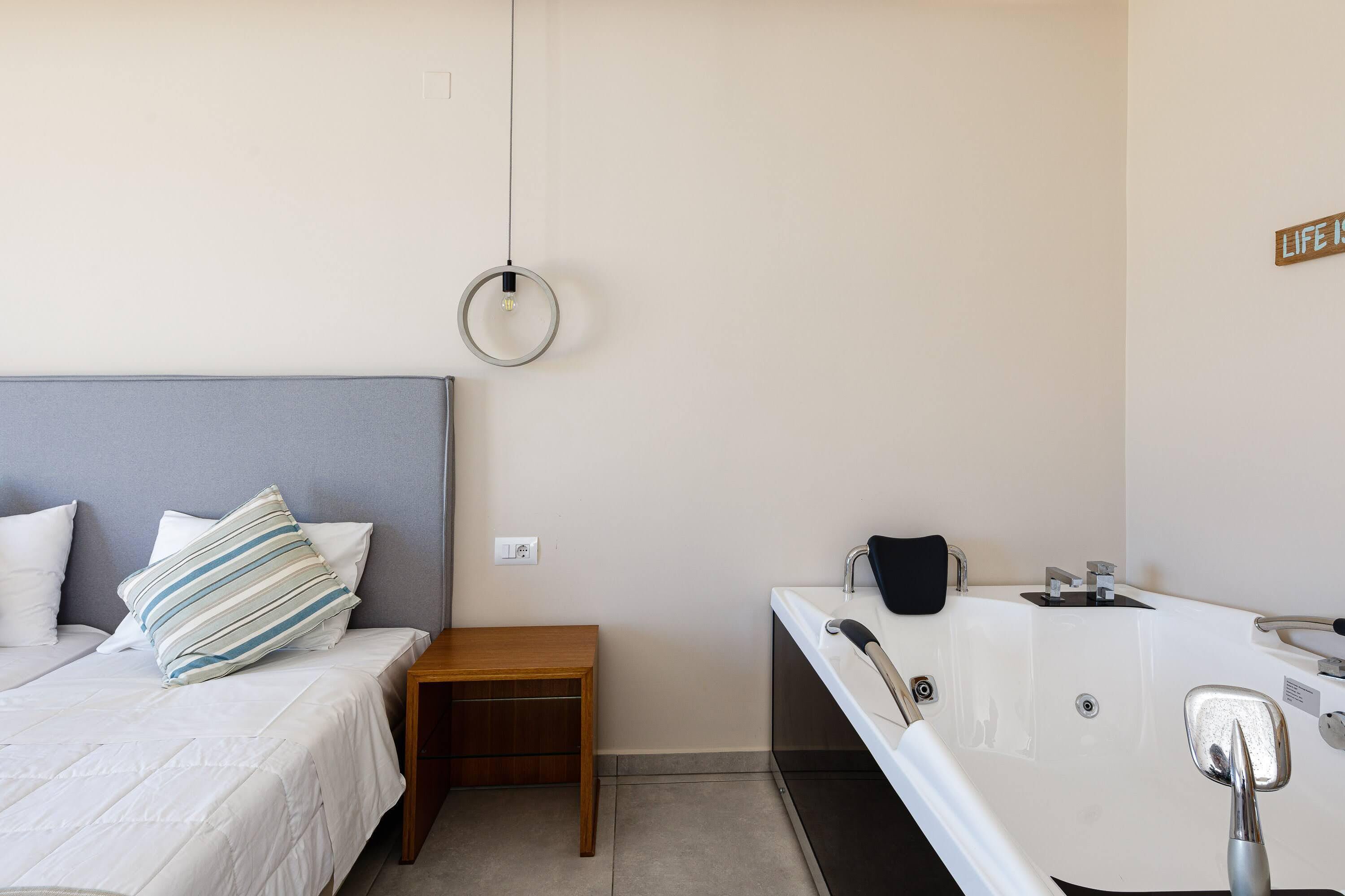 A bedroom with a bed, bedside table, and a wall-mounted light fixture.
