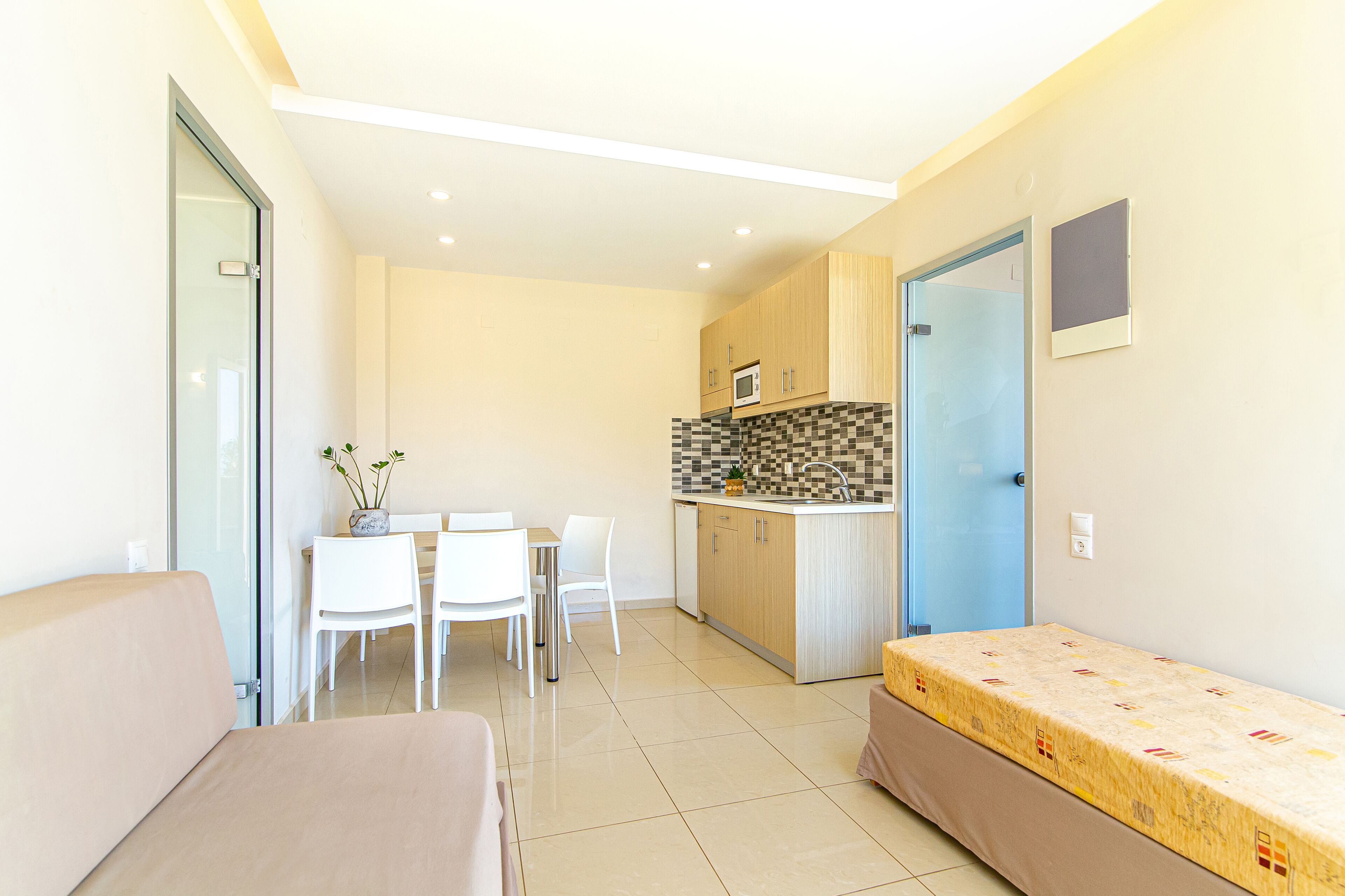 A compact living space with a kitchenette, a dining area, and a bed.