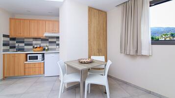 Uma cozinha moderna com armários de madeira, micro-ondas e uma mesa de jantar com cadeiras brancas.