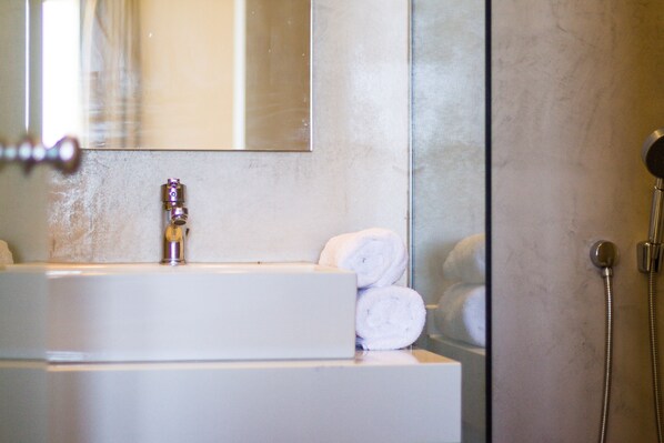 A bathroom with a sink, mirror, and shower.