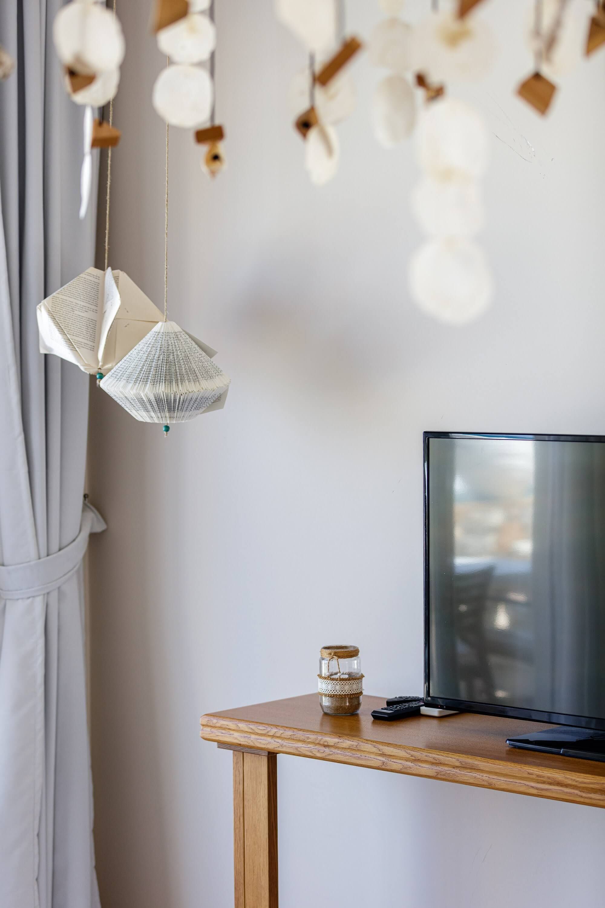 A room with a wooden table, a television, and hanging paper lanterns.