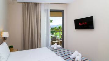 A hotel room with a bed, a TV displaying 'NETFLIX', a window with curtains, and a view of a garden.