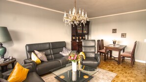 Ein modernes Wohnzimmer mit Glastisch, Ledersofa und einer Kronleuchter.