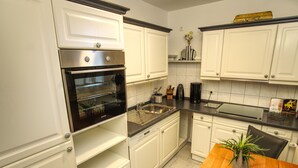 Eine Küche mit weißen Schränken, einem schwarzen Backofen, einem Holztisch mit einer Pflanze und einer schwarzen Arbeitsplatte.