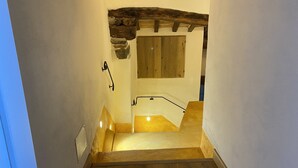 A narrow staircase with a wooden handrail, a stone wall on one side, and a wooden door at the top. - The Old Fashion House (Cortona)