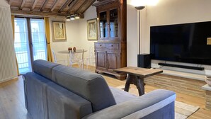 A living room with a grey sofa, a wooden table, a TV, and a cabinet. - The Old Fashion House (Cortona)