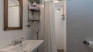 A bathroom with a white sink, a mirror, a shower with a curtain, and a towel rack.