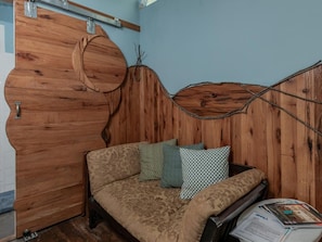 Ein Zimmer mit einem hölzernen Kopfteil, einer Couch mit gemusterten Kissen und einem kleinen Tisch mit Zeitschriften.