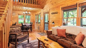 Een houten chalet inrichting met een eethoek, een bank en een wenteltrap.